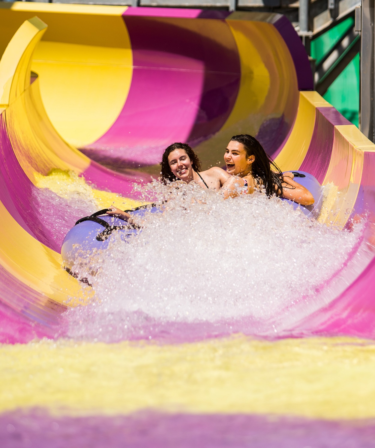 two girls on a pink and yellow water slide